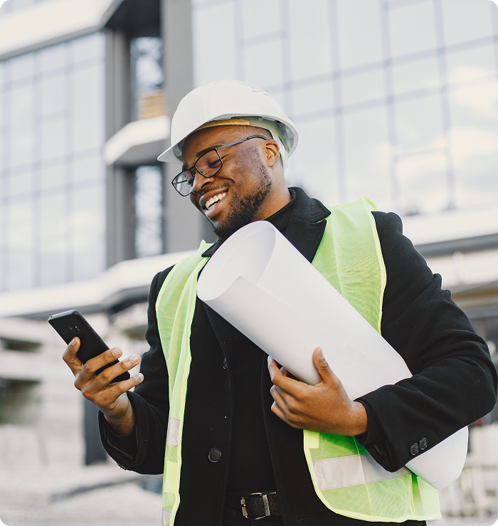 Smiling engineer holding plans and phone